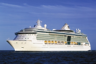 The image shows a large white cruise ship, the Brilliance of the Seas, sailing on calm blue waters under a clear sky.