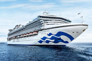 image of the front of the Diamond Princess cruise ship gliding through the calm waters featuring the cloudy skies