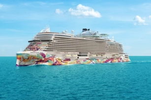 Image of the Norwegian Aqua cruise ship featuring the colourful base of the ship, gliding through clear blue waters