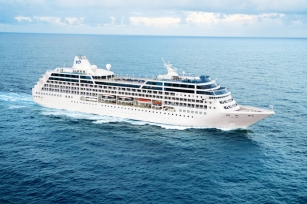 Aerial view of the Ocean Princess gliding through the clear blue waters featuring the cloudy skies
