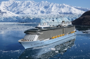 image of the front of the Ovation of the Seas against the snow covered lands as it sails through the sea