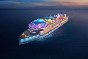 Star of the Seas lit up as it sails across the sea at dusk